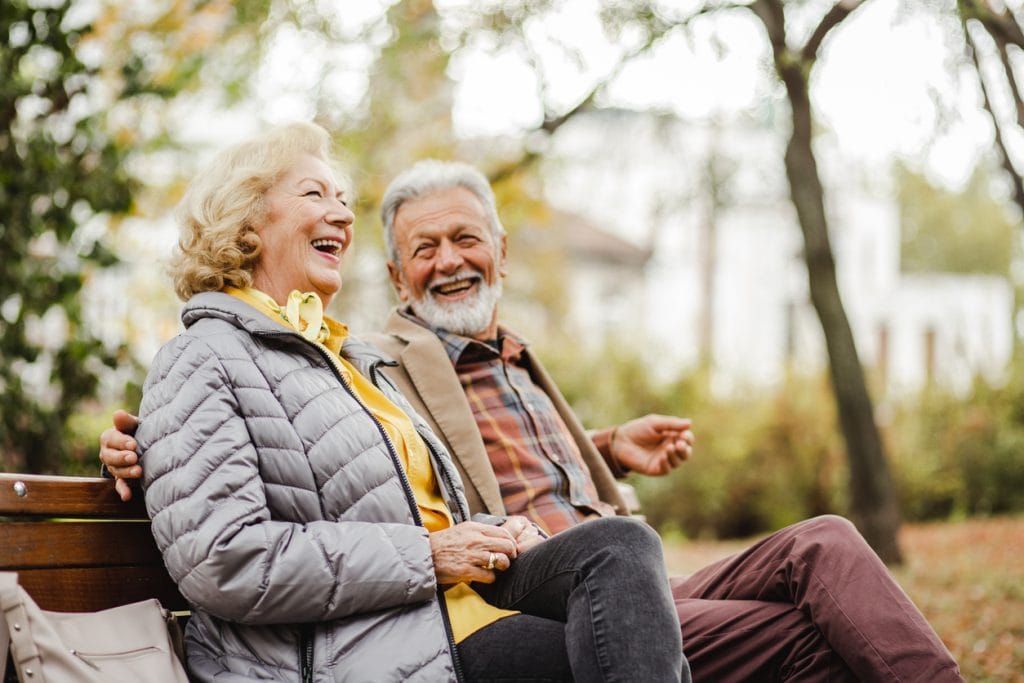 couple sitting together on a park bench enjoying their retirement 