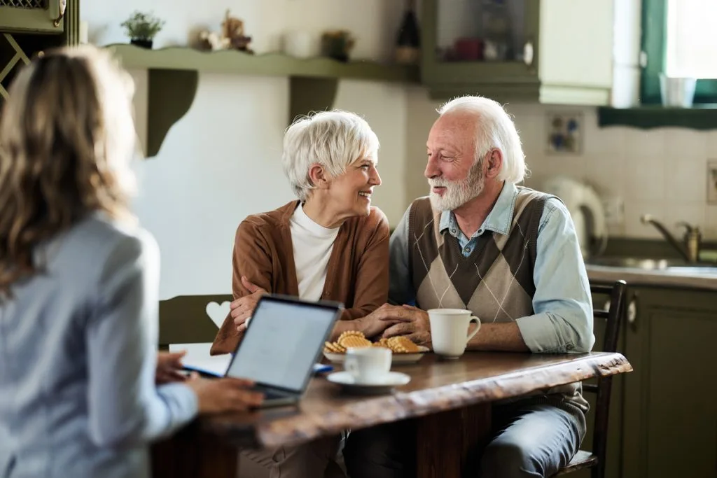 Elderly couple discussing equity release with an adviser at a table in their home